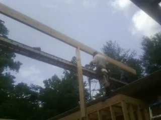 Carpenter setting a ridge beam over a new addition frame — Ice Dam Removal by Roofing Brothers in Elkin