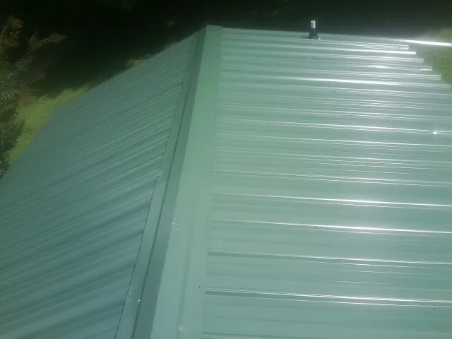 New green metal panels meeting at the ridge of a roof — Flat Roof Repair work by our crew in Elkin
