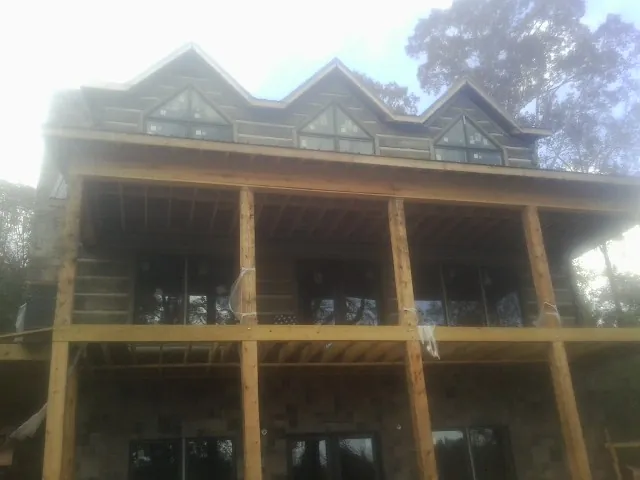 Dormers and porch framing on a large log home under construction — Roof Coating work by our crew in Elkin