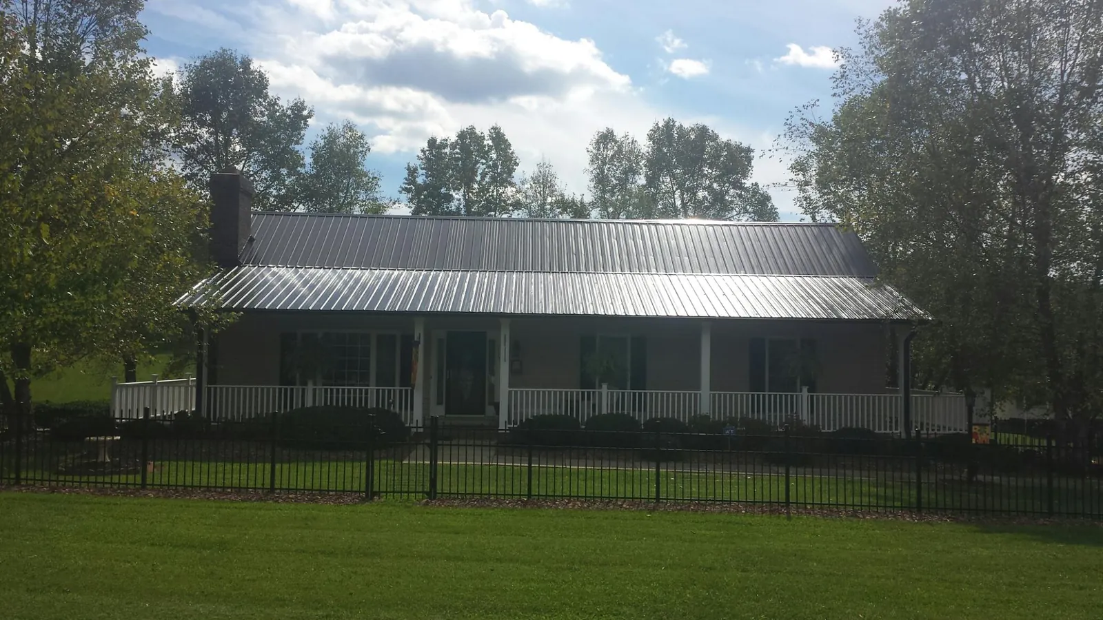 Gray metal roof on a brick ranch with a full width front porch — Gutter Guard Installation work by our crew in Elkin