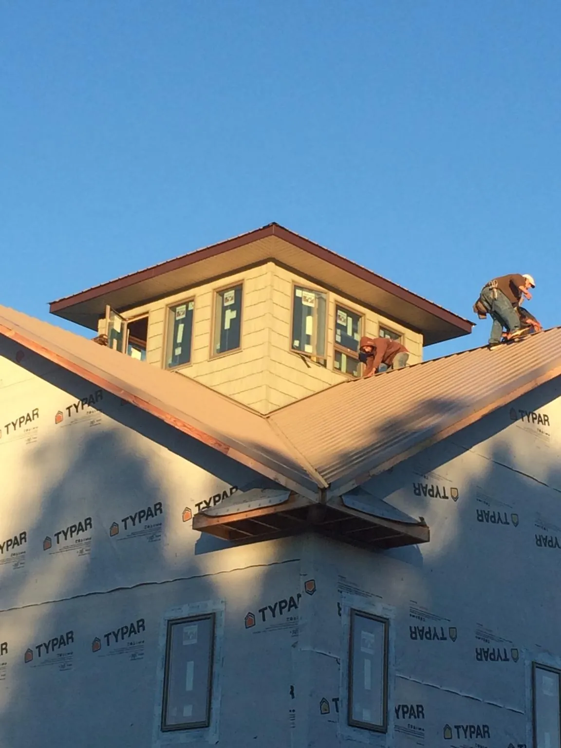 Roofers working around a rooftop cupola on a new metal roof at sunset — Roof Waterproofing in Elkin by Roofing Brothers